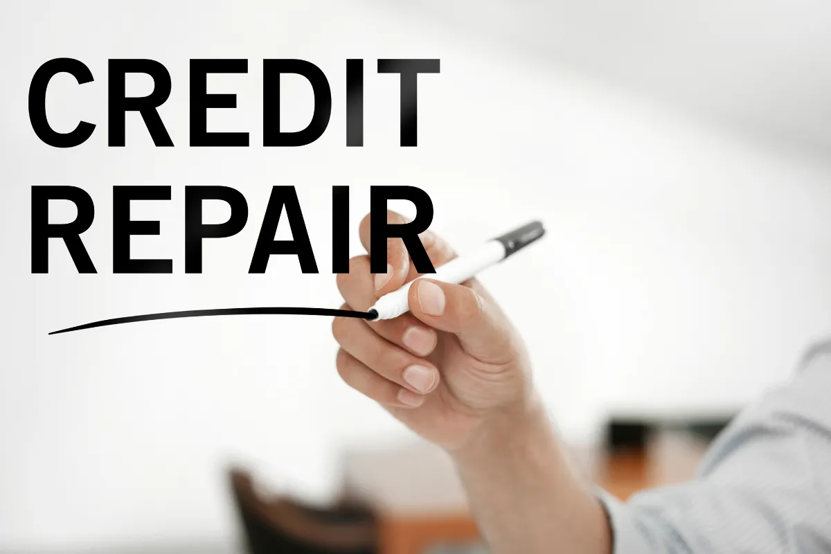 A hand writing the words 'CREDIT REPAIR' with a marker on a clear surface.