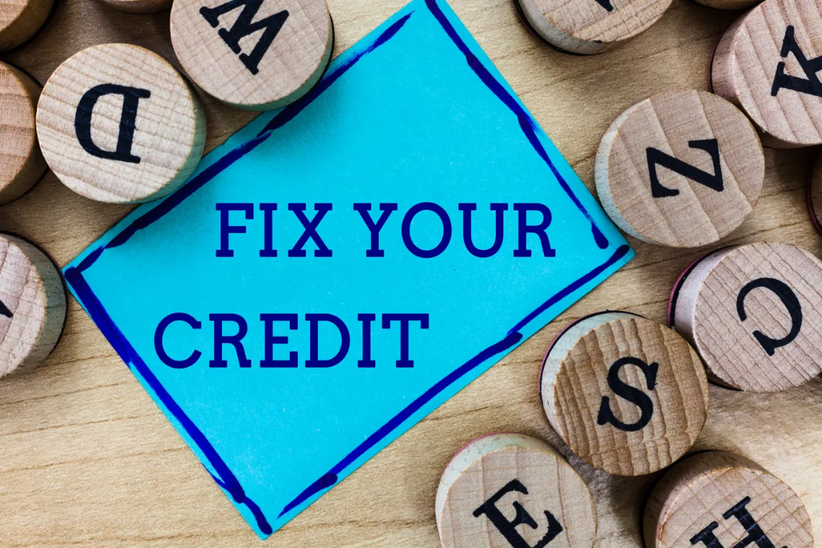 A sign reading 'FIX YOUR CREDIT' amidst scattered wooden letter tiles.