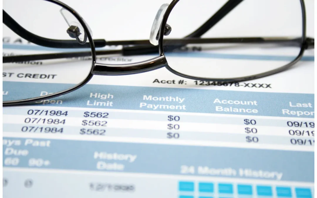 Eyeglasses on a credit report highlighting financial details and obscured account numbers.