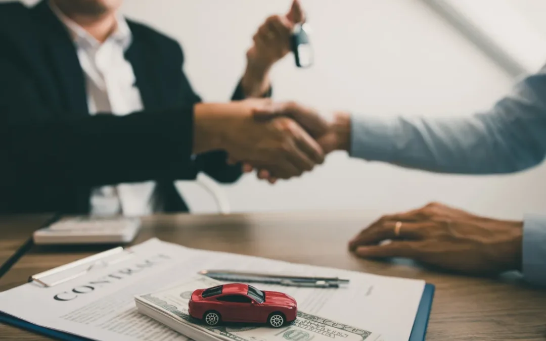 Handshake over a table with a contract, toy car, and cash, suggesting a vehicle transaction.